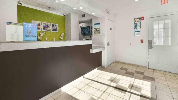 A reception area with a counter, a green wall, and an exit sign. - 2 Beds | Smoking, Deluxe (Tucker)