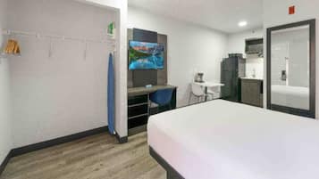 Een hotelkamer met een bed, een bureau, een stoel, een televisie en een kledingkast.