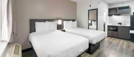 A hotel room with two beds, a kitchenette, and a bathroom.