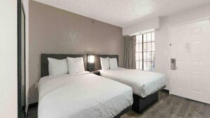 Una habitación de hotel con dos camas, un ventanal grande y una puerta.