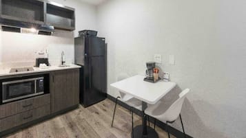Een praktische keuken met een magnetron, oven, koelkast en een eettafel met stoelen.
