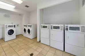 Una sala de bugaderia amb quatre rentadores i un paviment de rajoles.