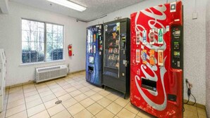 Una habitación con ventana, radiador y máquinas expendedoras, incluyendo una de Coca-Cola.