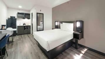 Una habitación de hotel con una cama, una mesita de noche y un escritorio con silla.