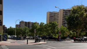 Una intersección urbana con semáforo, paso de peatones y edificios al fondo.