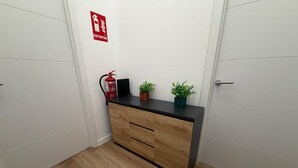 Una habitación con un escritorio de madera, un extintor y dos plantas en macetas.