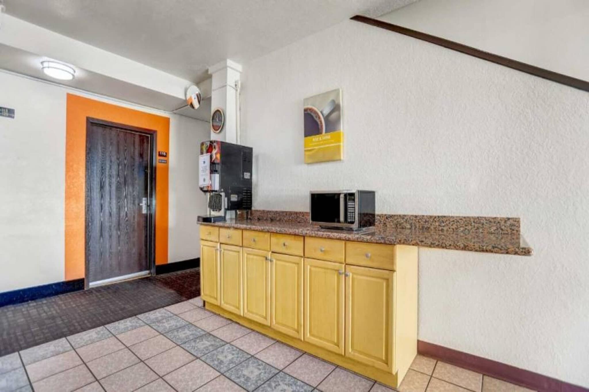 A small kitchenette with a microwave, a coffee machine, and a tiled floor.