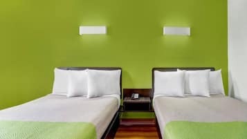 Hotellihuone, jossa on kaksi erillistä sänkyä, puulattia ja vihreä seinä.
