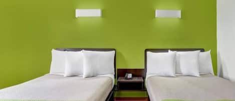 Een hotelkamer met twee eenpersoonsbedden, een houten vloer en een groene wand.