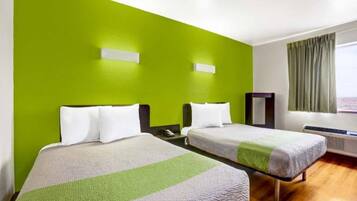 A hotel room with two beds, a large window with curtains, and a heater.