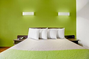 A hotel room with a bed, green walls, two bedside tables, and a telephone on one of the tables.