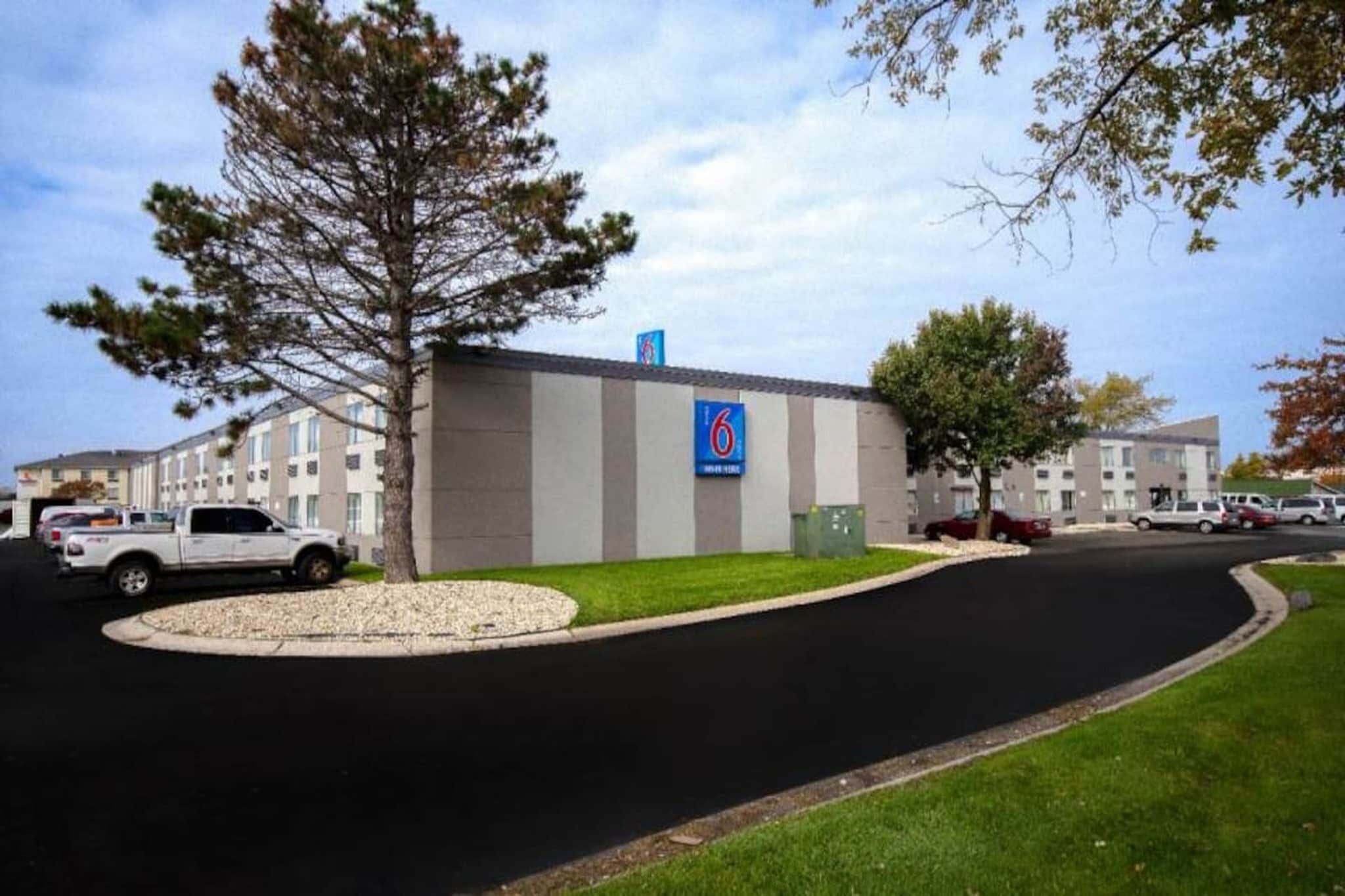 A building with a sign indicating it is a motel, surrounded by parked cars and a grassy area.
