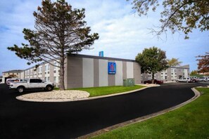 Un bâtiment sur lequel est apposée une enseigne indiquant qu’il s’agit d’un motel, entouré de voitures garées et d’une zone herbeuse.