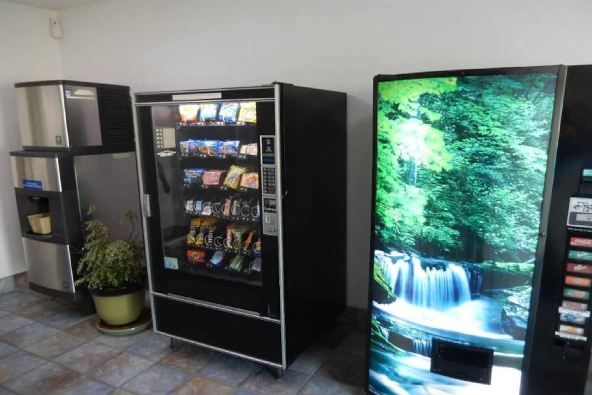 Máquina de vendas com lanches e uma tela de televisão exibindo uma cascata.