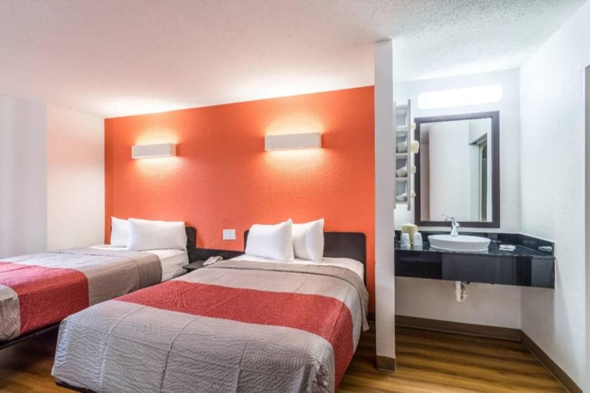 Ein Hotelzimmer mit zwei Betten, einem großen Spiegel und einem modernen Badezimmer.