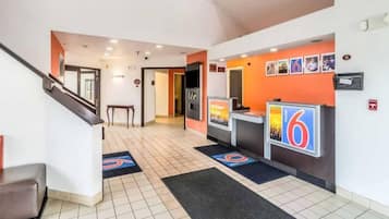 Ein Hotel-Empfangsbereich mit einer Rezeption, einer Treppe und einem an der Wand befestigten Schild.