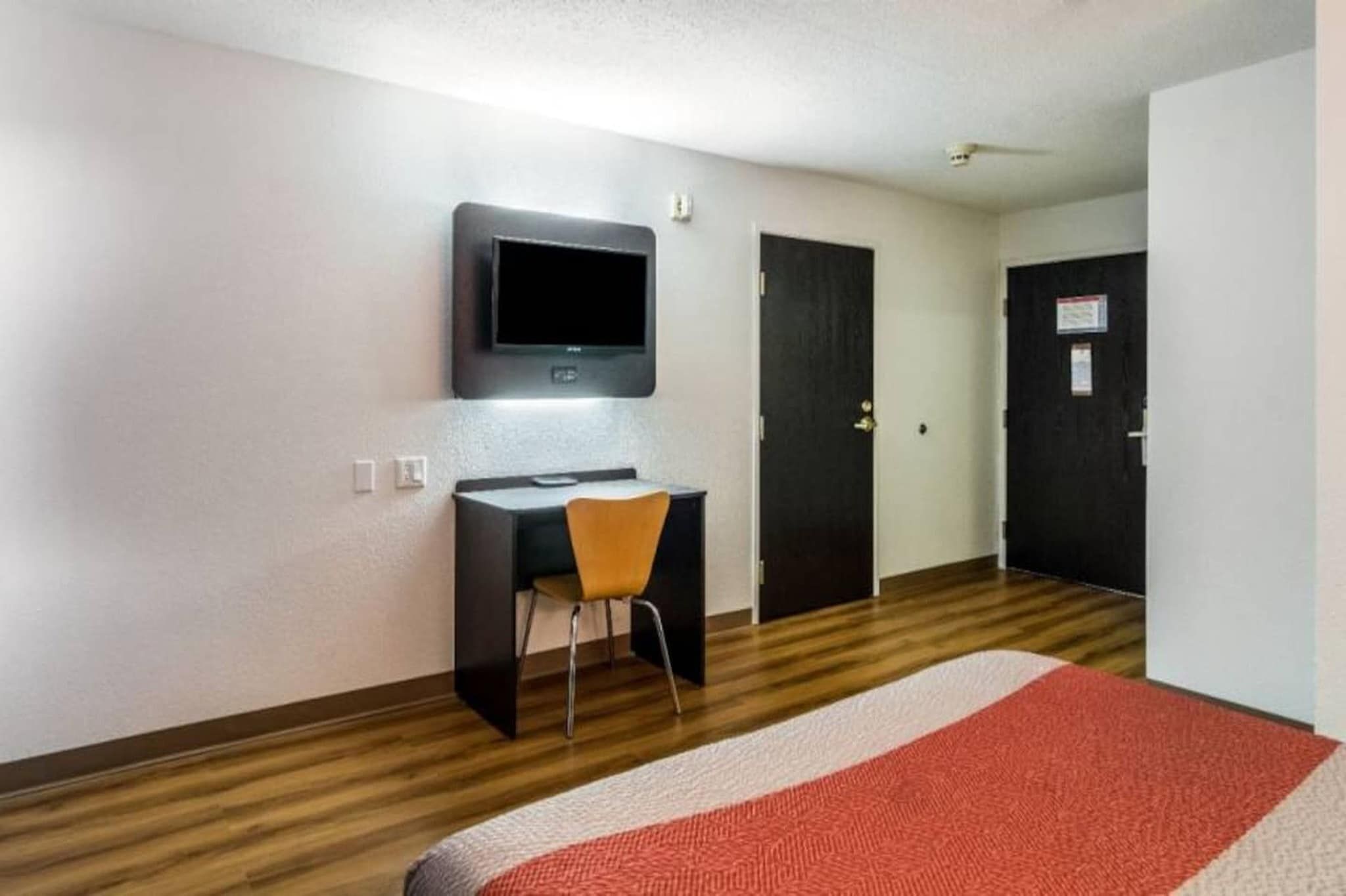 Une chambre d’hôtel équipée d’un bureau, d’une chaise, d’une télévision et de deux portes.