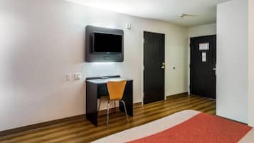 Une chambre d’hôtel équipée d’un bureau, d’une chaise, d’une télévision et de deux portes.