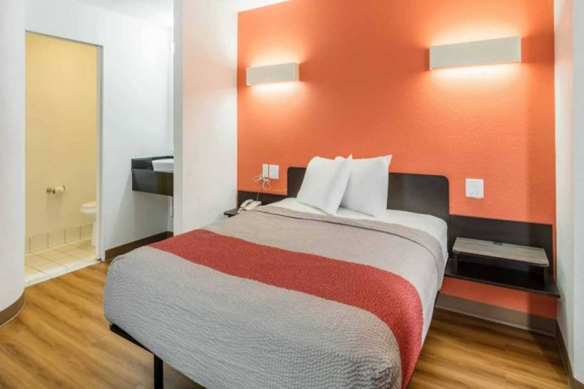 Ein Hotelzimmer mit Bett, Nachttischen, Telefon und einer Wandleuchte.