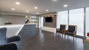 En moderne hotellobby med reception, siddeområde og store vinduer.