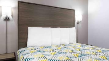 Ein Hotelzimmer mit einem Bett, einem Kopfteil, zwei Wandleuchten und einem Nachttisch.