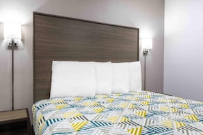 A hotel room with a bed, a headboard, two wall-mounted lights, and a nightstand. - 1 King Bed | Non-Smoking, Kitchen (Hickory)