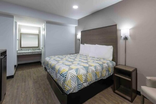 A hotel room with a bed, bedside table, and a small desk with a chair. - 1 King Bed | Non-Smoking, Kitchen (Hickory)