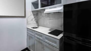 Una cocina con un refrigerador negro, un microondas, un lavamanos y una estufa.