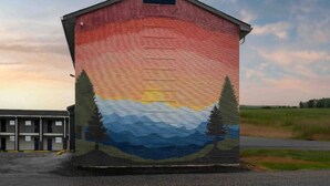Un edificio con un mural de una puesta de sol y monta ñas.