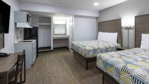 Habitación de hotel con dos camas, un escritorio, un microondas y un armario.