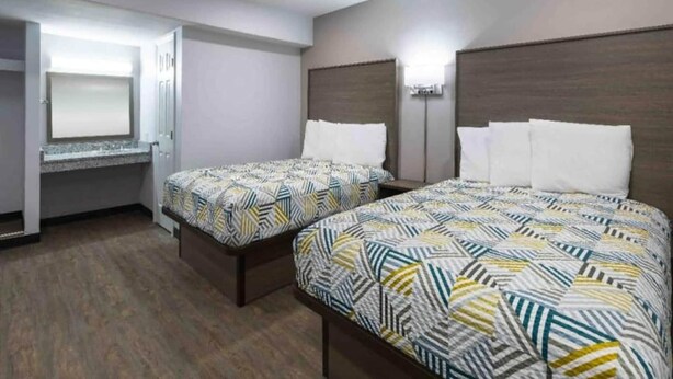 Habitación de hotel con dos camas, un escritorio y un espejo.