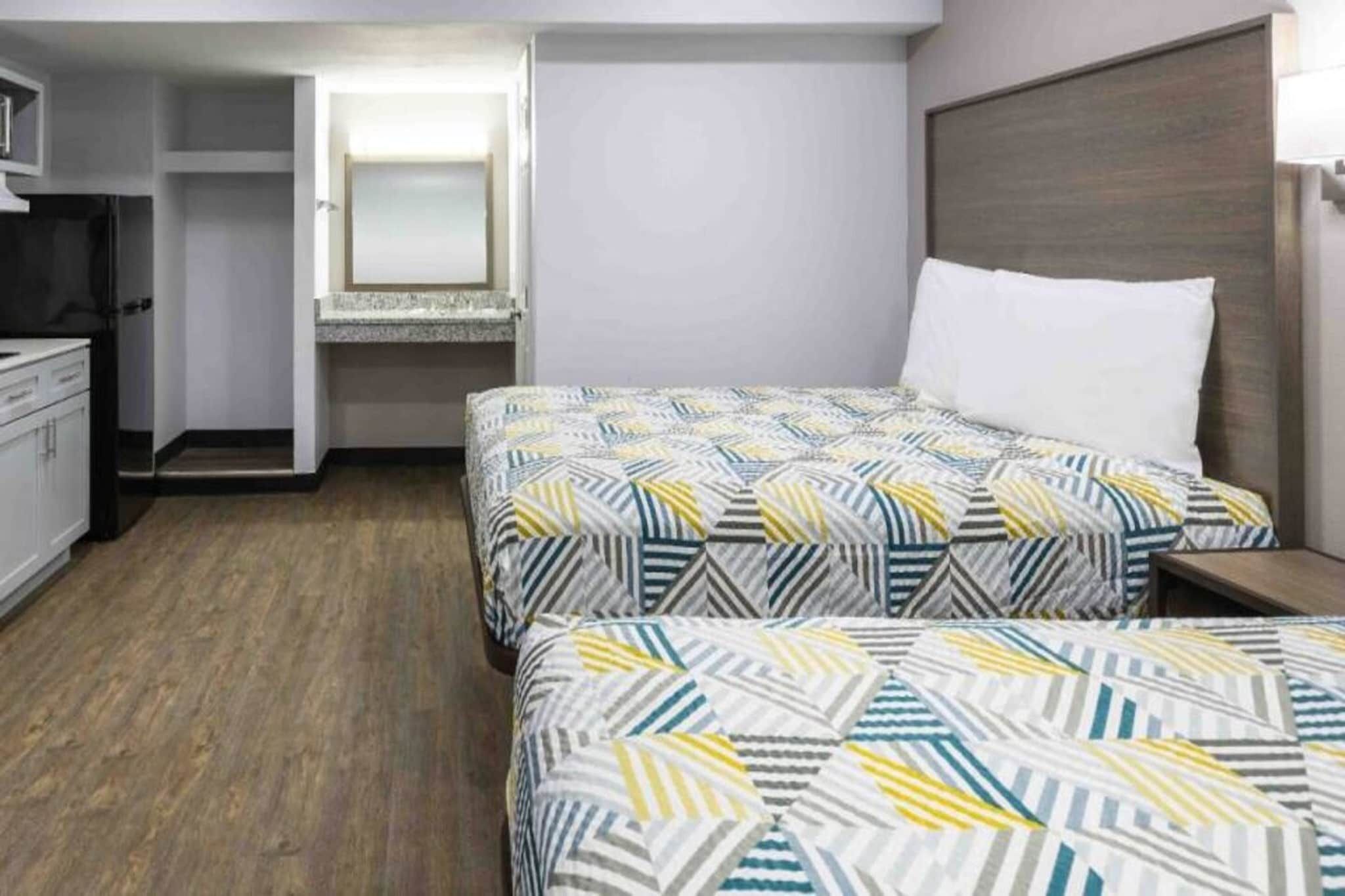 A hotel room with two beds, a desk, and a wardrobe.