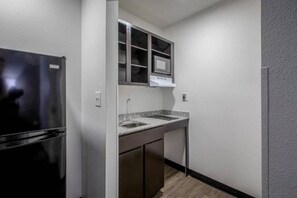 A compact kitchen with a refrigerator, a double sink, and a microwave.