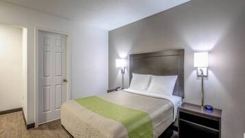 Een hotelkamer met een bed, nachtkastjes en een deur.
