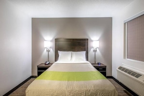 Habitació d'hotel amb un llit, dues taules de nit i un radiador penjat a la paret.