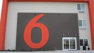 A building with a large red number '6' on the facade, a white door, and a small window to the right.