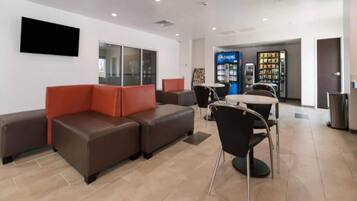 A modern waiting area with leather seating, a vending machine, and a flat-screen TV mounted on the wall.