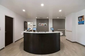 A reception desk with a curved black counter, two computer monitors, and a wall-mounted sign above. - 1 King Bed|Suite,Nsmk,Kitchen (Corpus Christi TX)