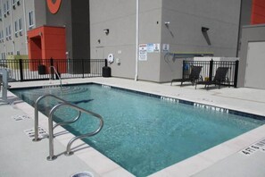 A swimming pool with a metal ladder, surrounded by a fence, and a lifebuoy on the wall. - 1 King Bed|Suite,Nsmk,Kitchen (Corpus Christi TX)
