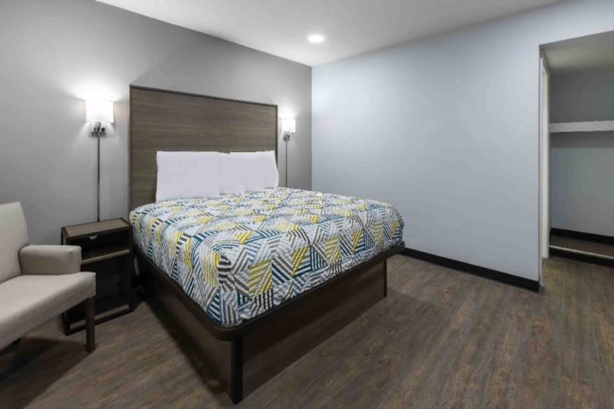 Ein Hotelzimmer mit einem Bett, einem Nachttisch, einem Sessel und einem Kleiderschrank.