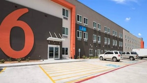 A modern building with a large '6' sign, a parking lot with marked spaces, and a clear sky. - 2 Queen Beds|Hearing Accessible,Kitchen (Corpus Christi TX)