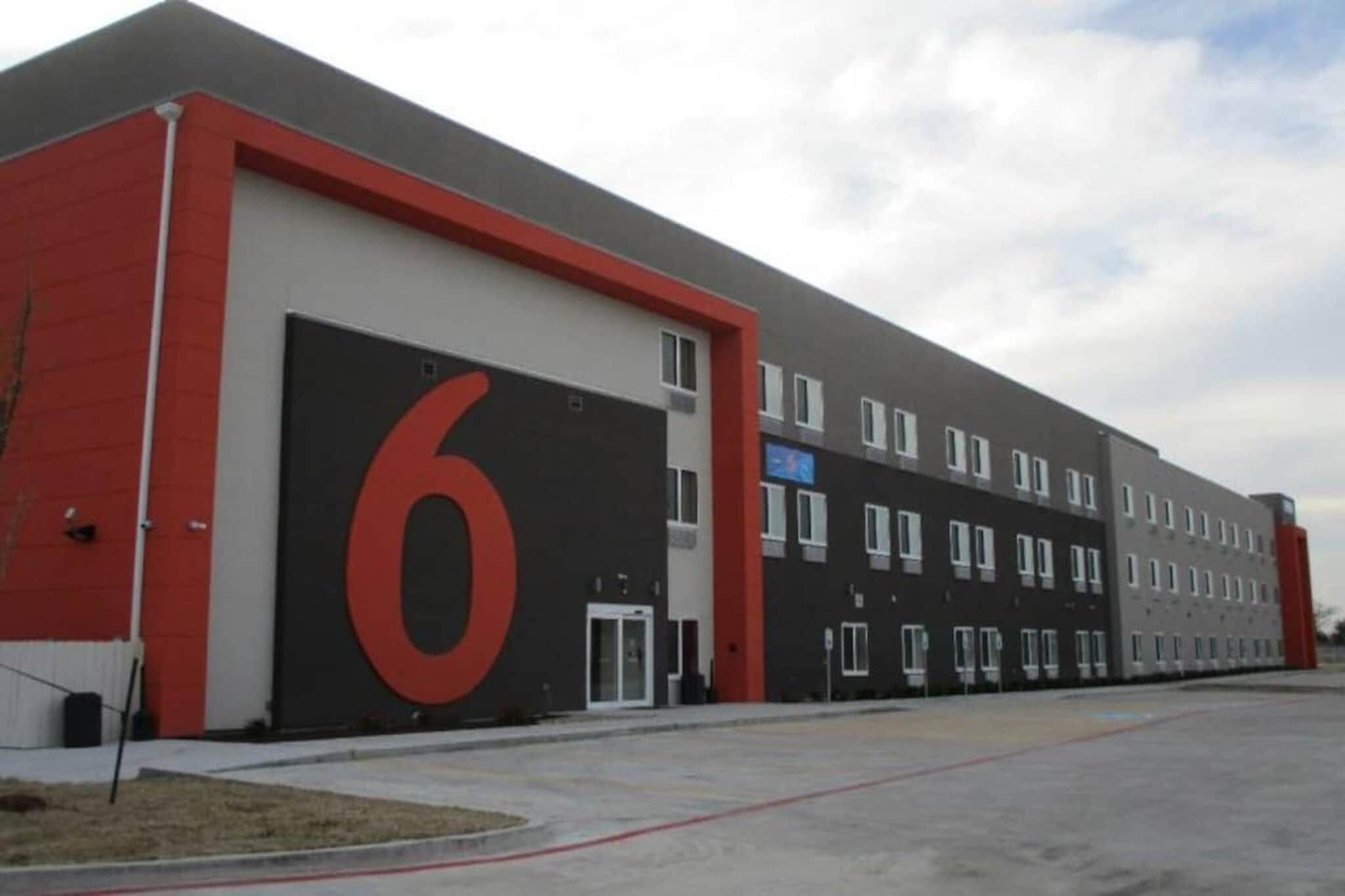 Un immeuble à plusieurs étages, doté d’une grande porte de garage et d’un chiffre « 6 » bien visible sur le côté.