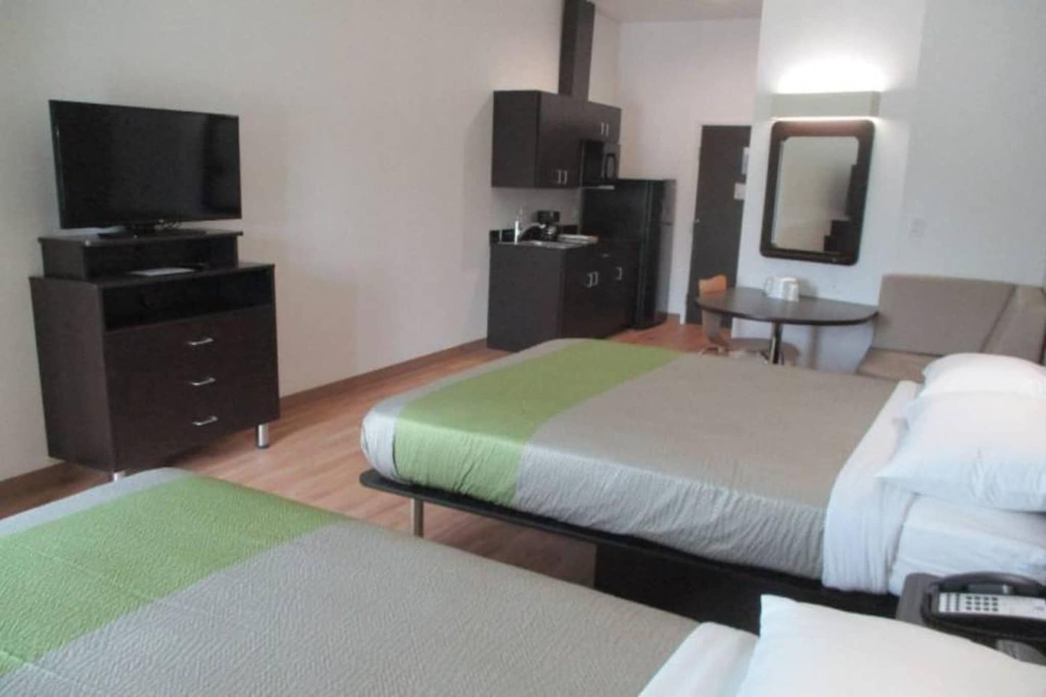 Habitación de hotel con dos camas, un escritorio, una silla, un televisor y un armario.