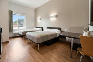 Quarto de hotel com duas camas, uma mesa de jantar e uma cadeira.