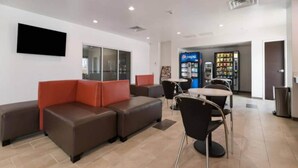 A modern waiting area with leather seating, a vending machine, and a flat-screen TV mounted on the wall. - 2 Queen Beds|Hearing Accessible,Kitchen (Corpus Christi TX)