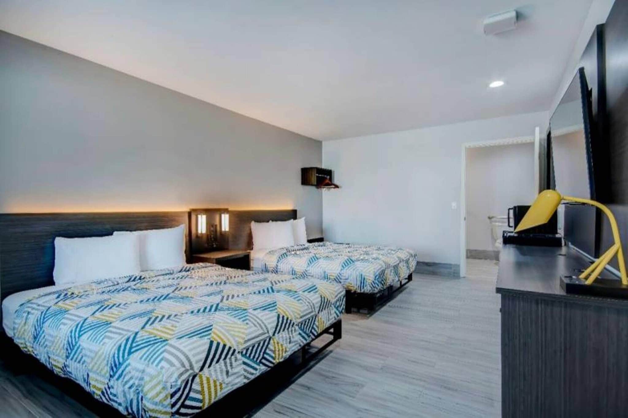 A hotel room with two beds, a desk, a chair, a TV, and a wardrobe.