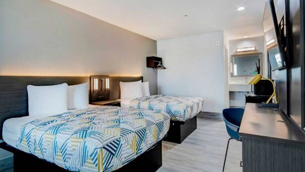Een hotelkamer met twee bedden, een bureau, een stoel en een spiegel.