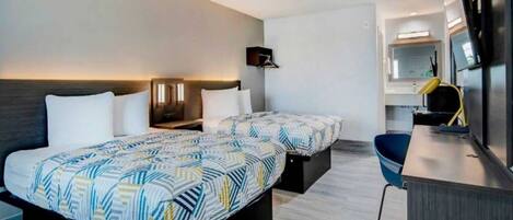 Une chambre d’hôtel avec deux lits, un bureau, une chaise et un miroir.
