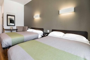 A hotel room with two beds, a small table, a chair, and a wall-mounted phone. - 2 Queen Beds | Mobility Accessible Tub Nsmk (Corpus Christi TX)