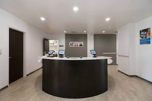 A reception area with a curved black counter, two computer monitors, and a door on the left. - 2 Queen Beds | Mobility Accessible Tub Nsmk (Corpus Christi TX)